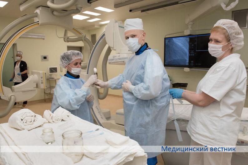 Рентгенэндоваскулярный хирург Дмитрий Шоцкий готовится к проведению операции. Ему помогают операционная медсестра Снежана Мороз и санитарка Наталья Середа